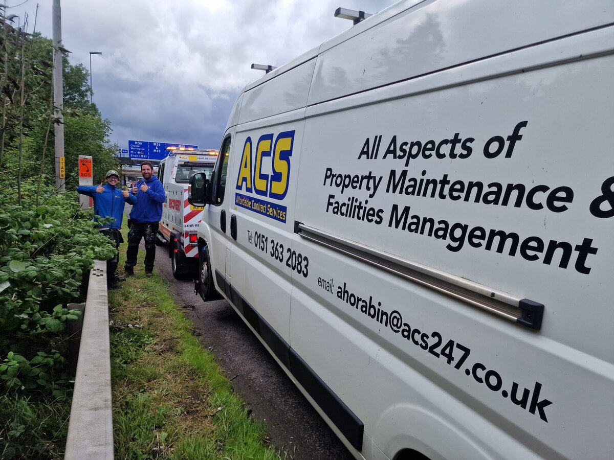 ACS Property Maintenance white panel van pulled in by the guardrail with two Breakdown Man crew alongside, ready to be loaded.