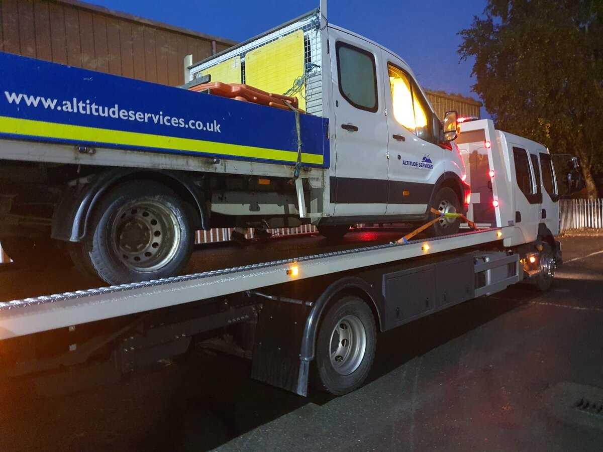 Breakdown Man recovering an Altitude Services Ford Transit dropside van on the flatbed at night.