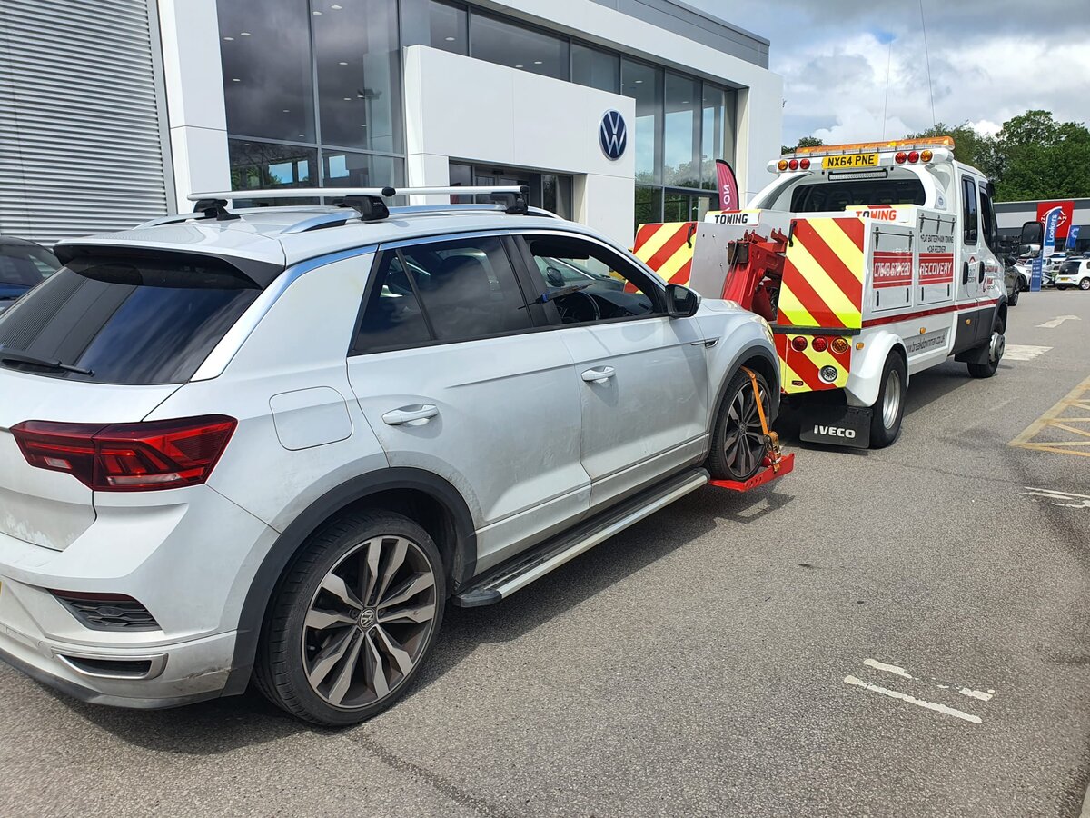 Silver Volkswagen T-Roc loaded onto a Breakdown Man Iveco flatbed truck outside a VW dealership for transport back to Atherton.