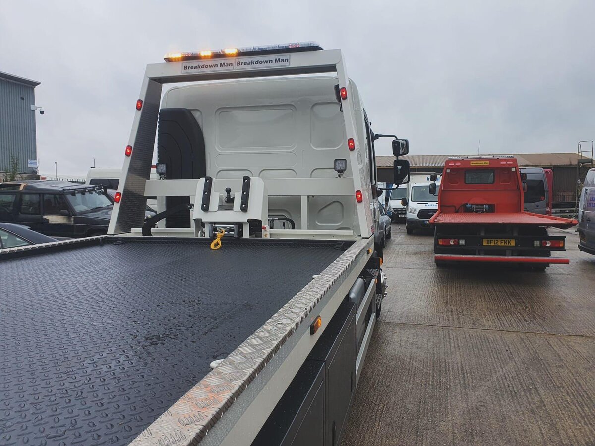Breakdown Man flatbed recovery truck parked at a Volkswagen dealership ready for a car towing job.