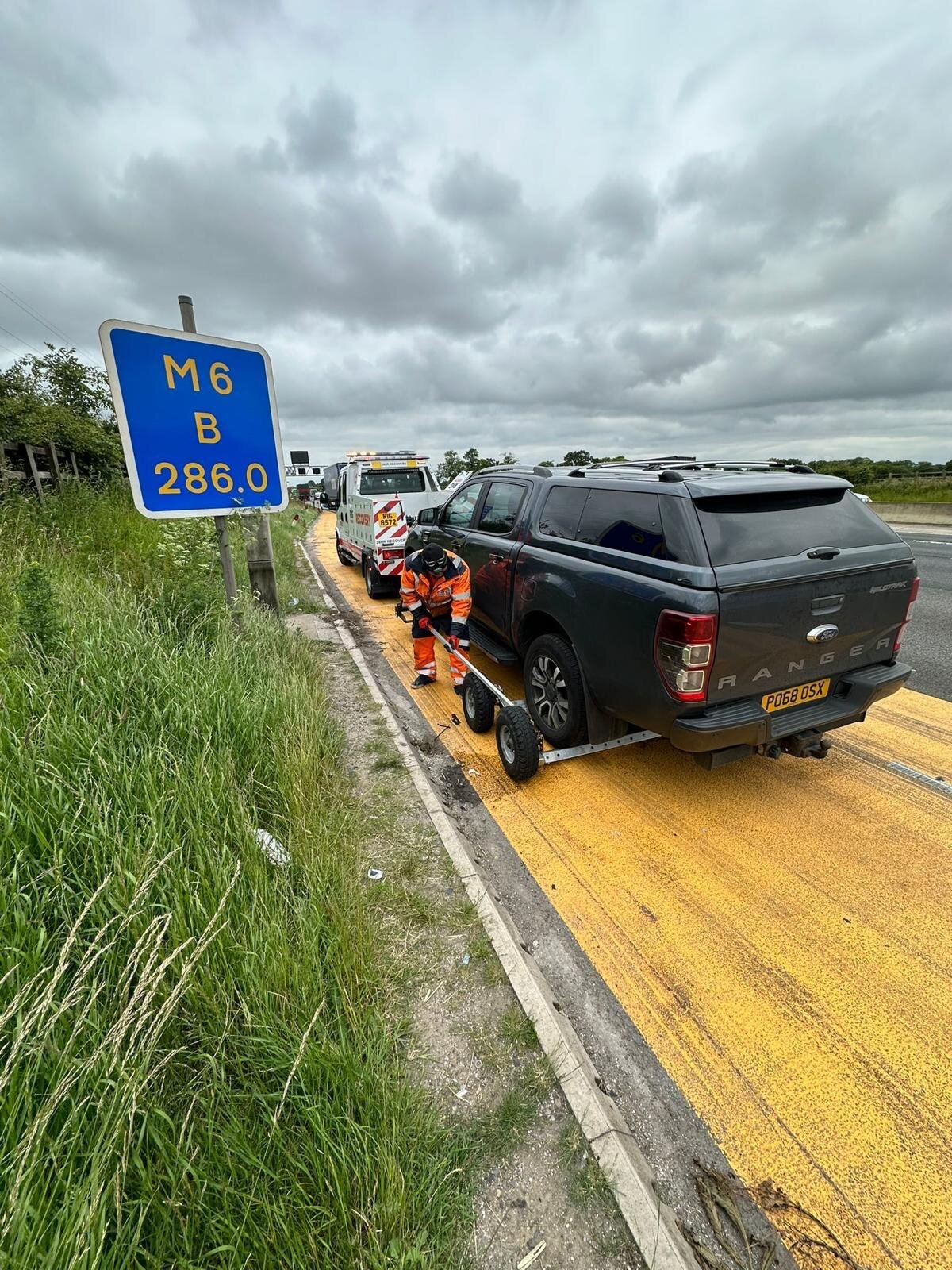 Simon in hi-vis loading a Ford Ranger pickup onto the Breakdown Man flatbed on the M6 hard shoulder near marker post B 286.0.